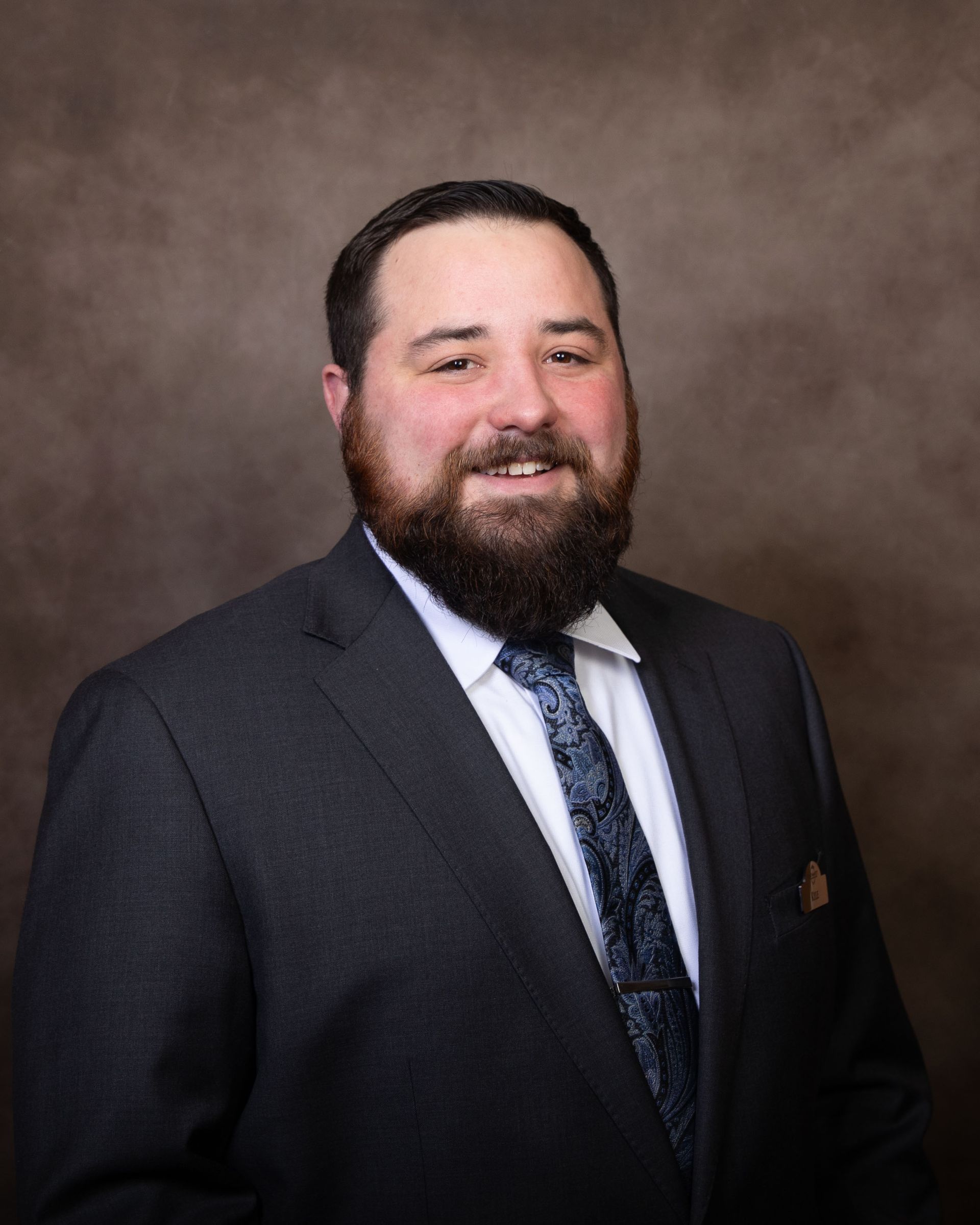 A man with a beard is wearing a suit and tie.