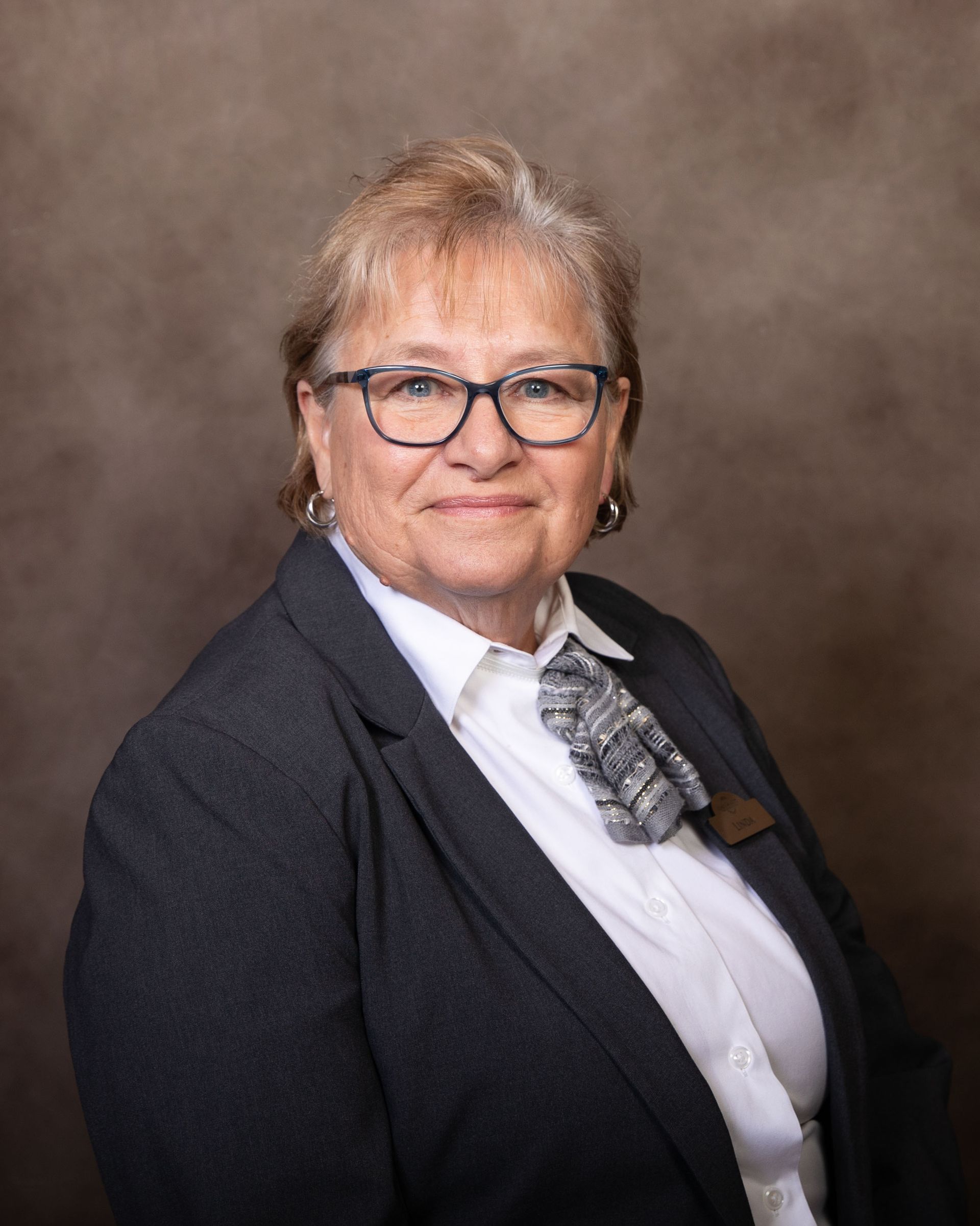 A woman in a suit and tie is smiling for the camera.