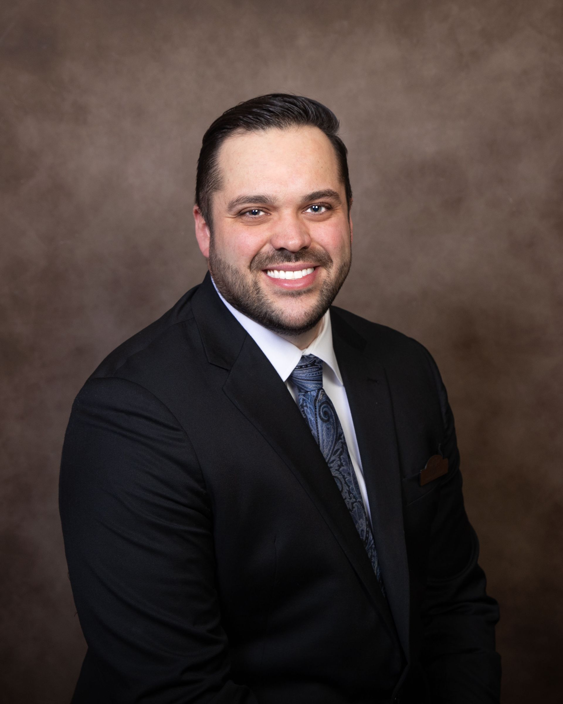 A man in a suit and tie is smiling for the camera.