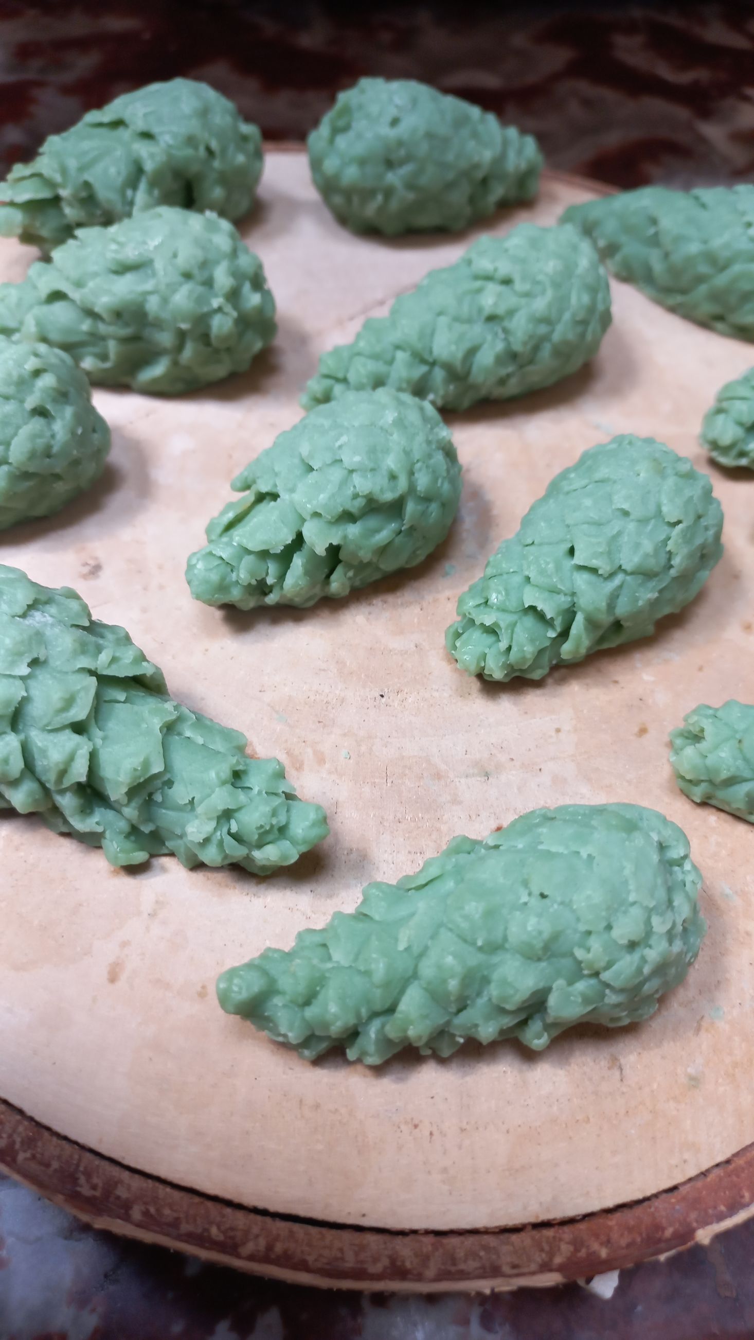 Hand plaatst gedroogde lavendel in een glazen kom met kruiden en stukken zeep op een tafel.