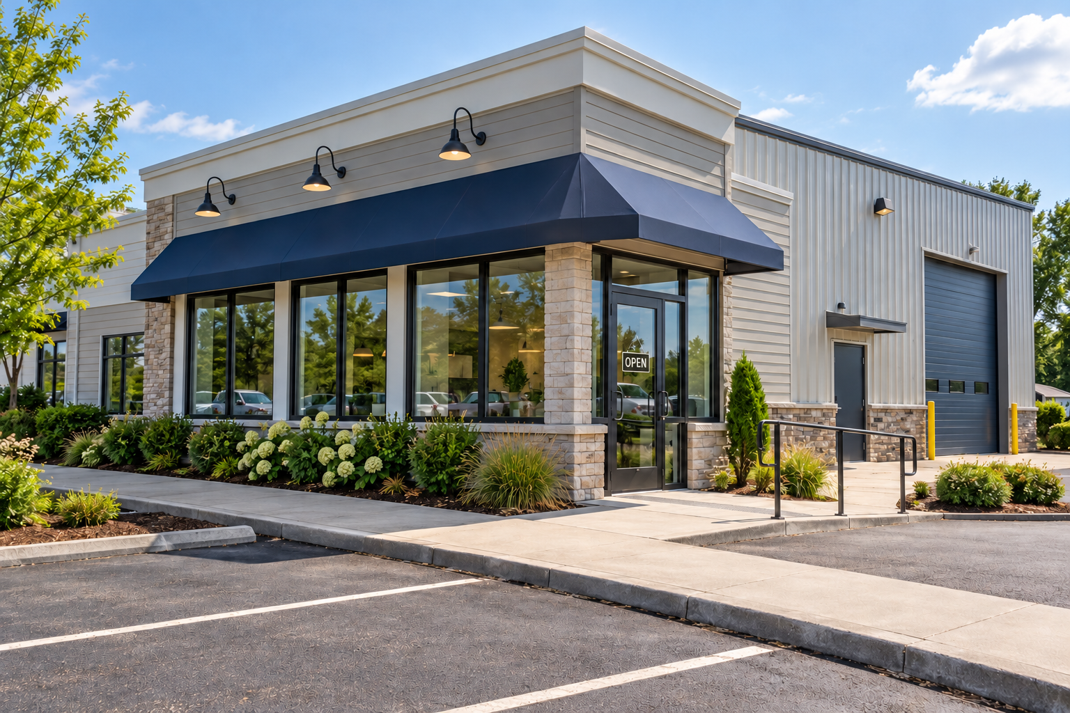 Modern storefront with black awning, large windows, and a landscaped parking lot in front