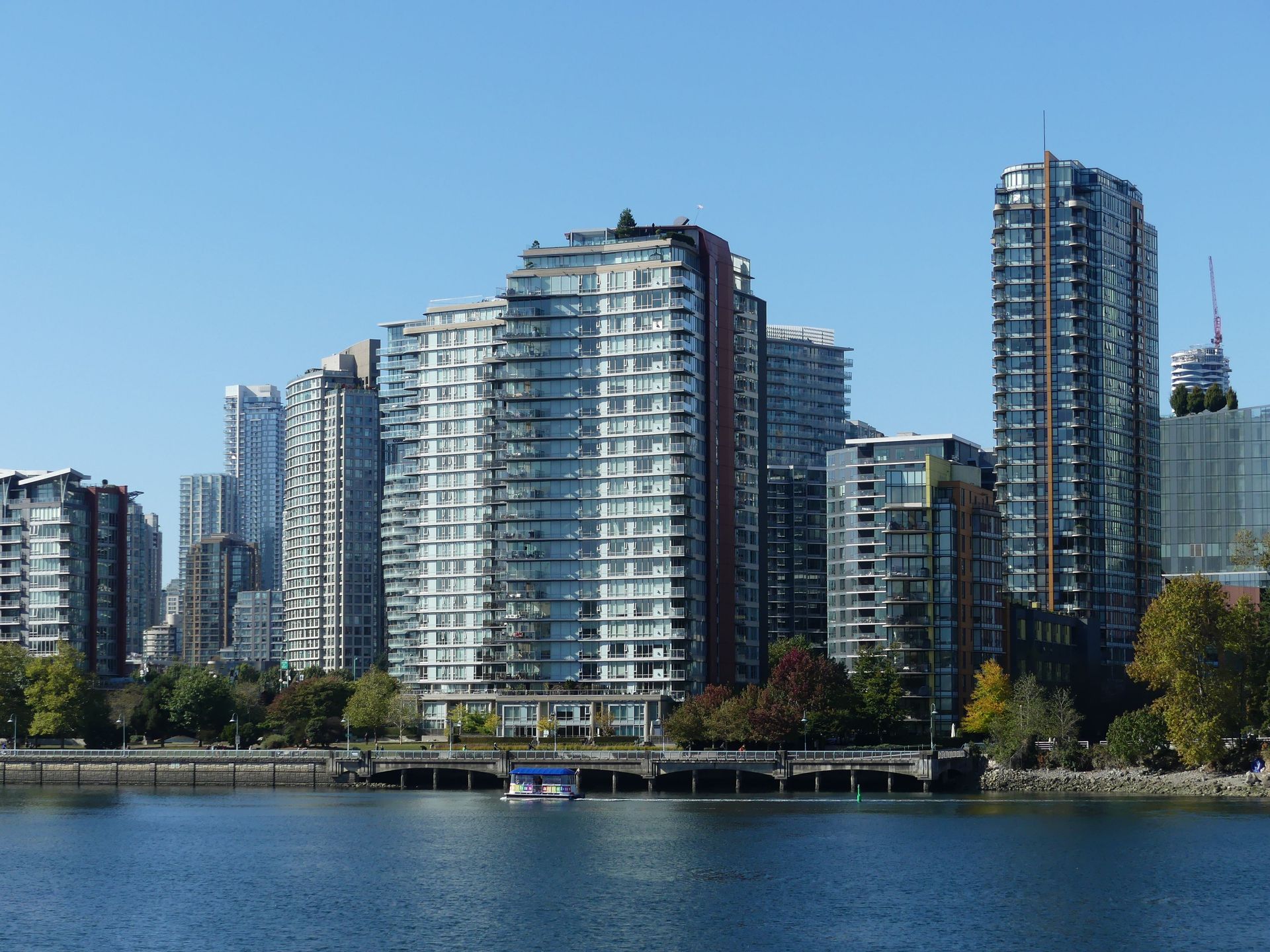 Waterfront skyline with modern high-rise condos beside a calm bay under a clear blue sky
