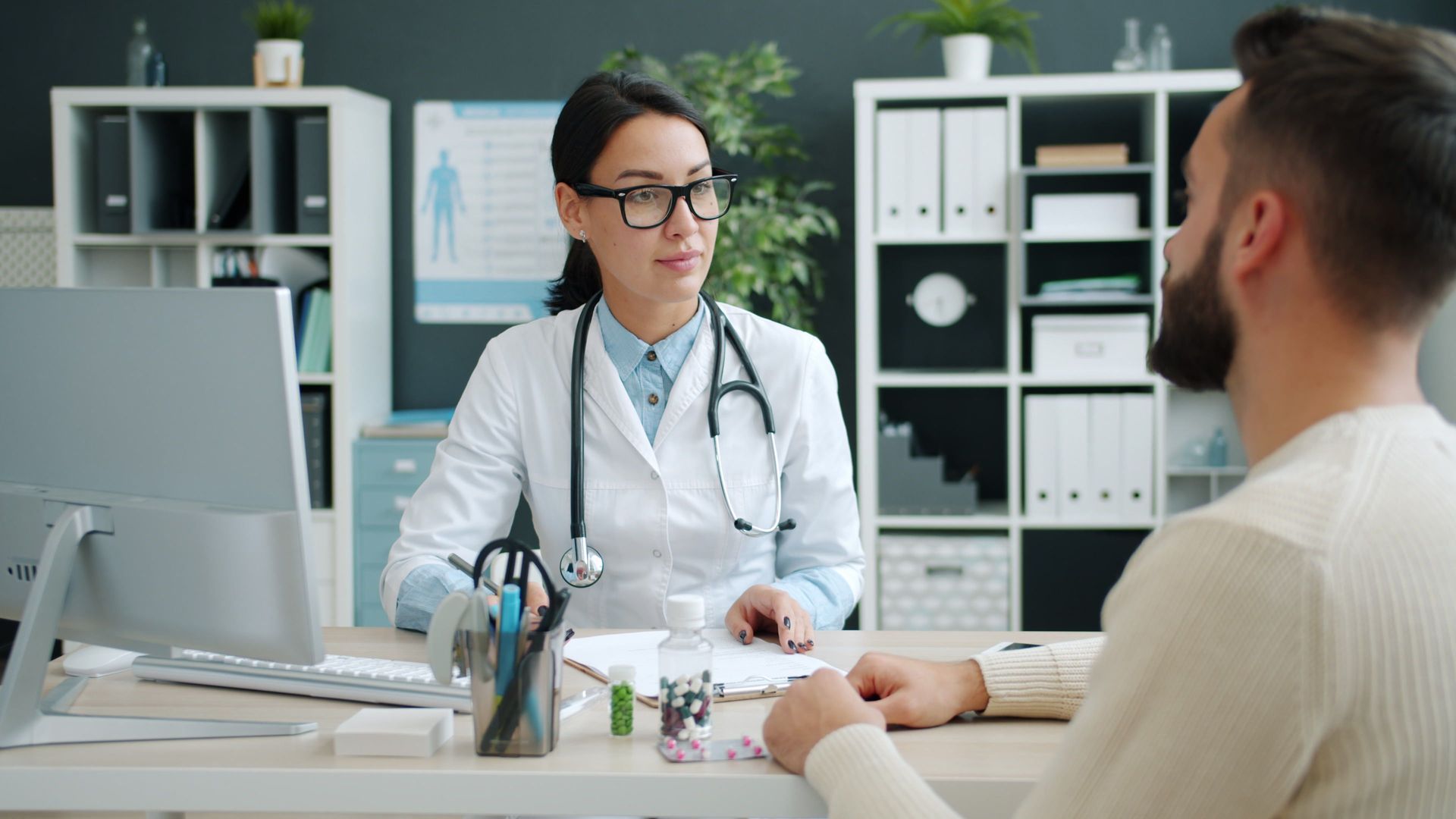 Doctor consulting with a patient at a desk in a bright clinic office.