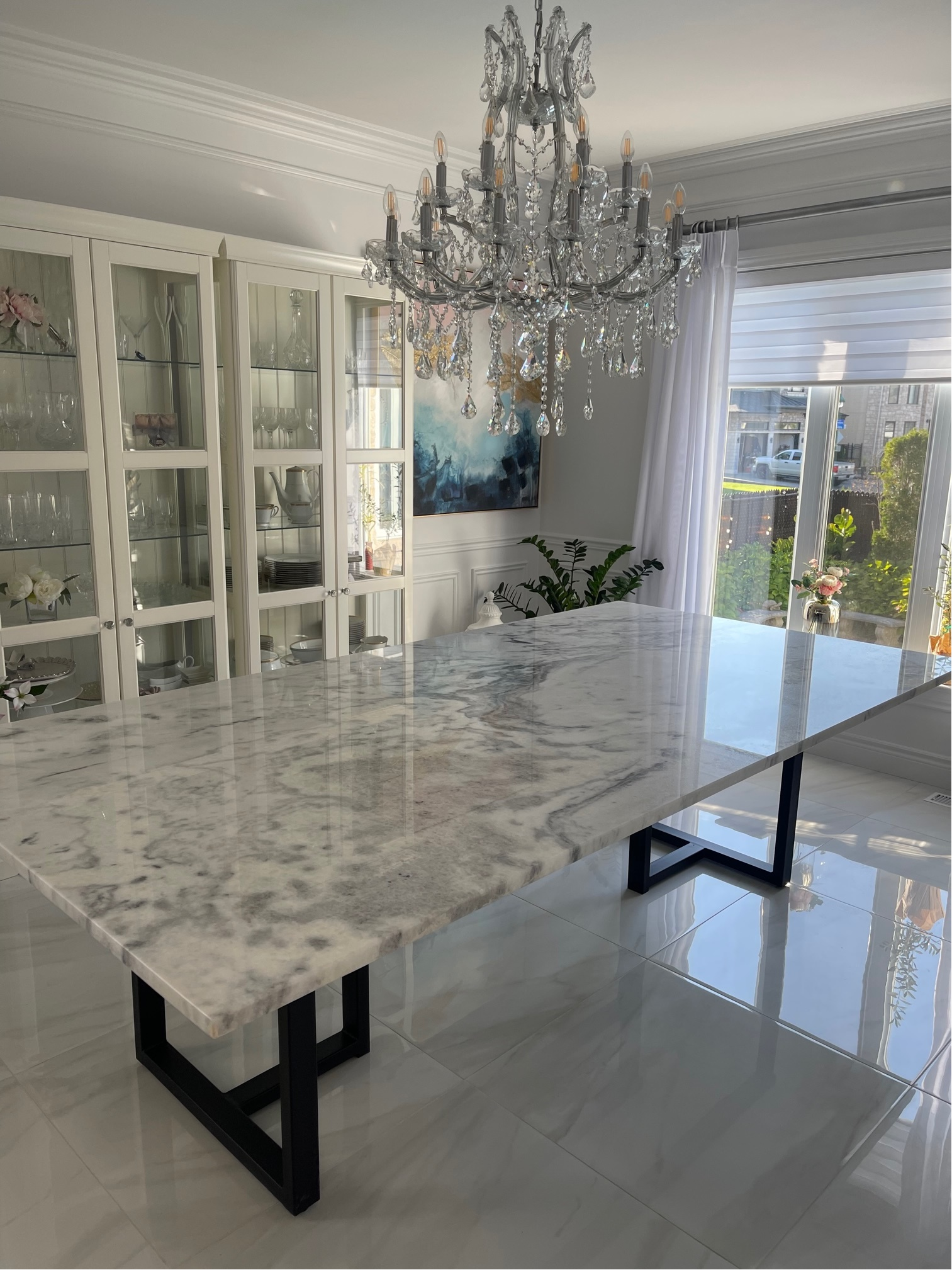 Une table à manger en marbre dans une salle à manger avec un lustre suspendu au plafond.