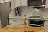 Une bouteille de sauce piquante est posée sur une planche à découper en bois dans une cuisine.