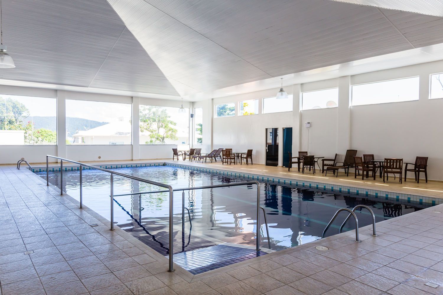 Uma grande piscina coberta com cadeiras e mesas ao redor.