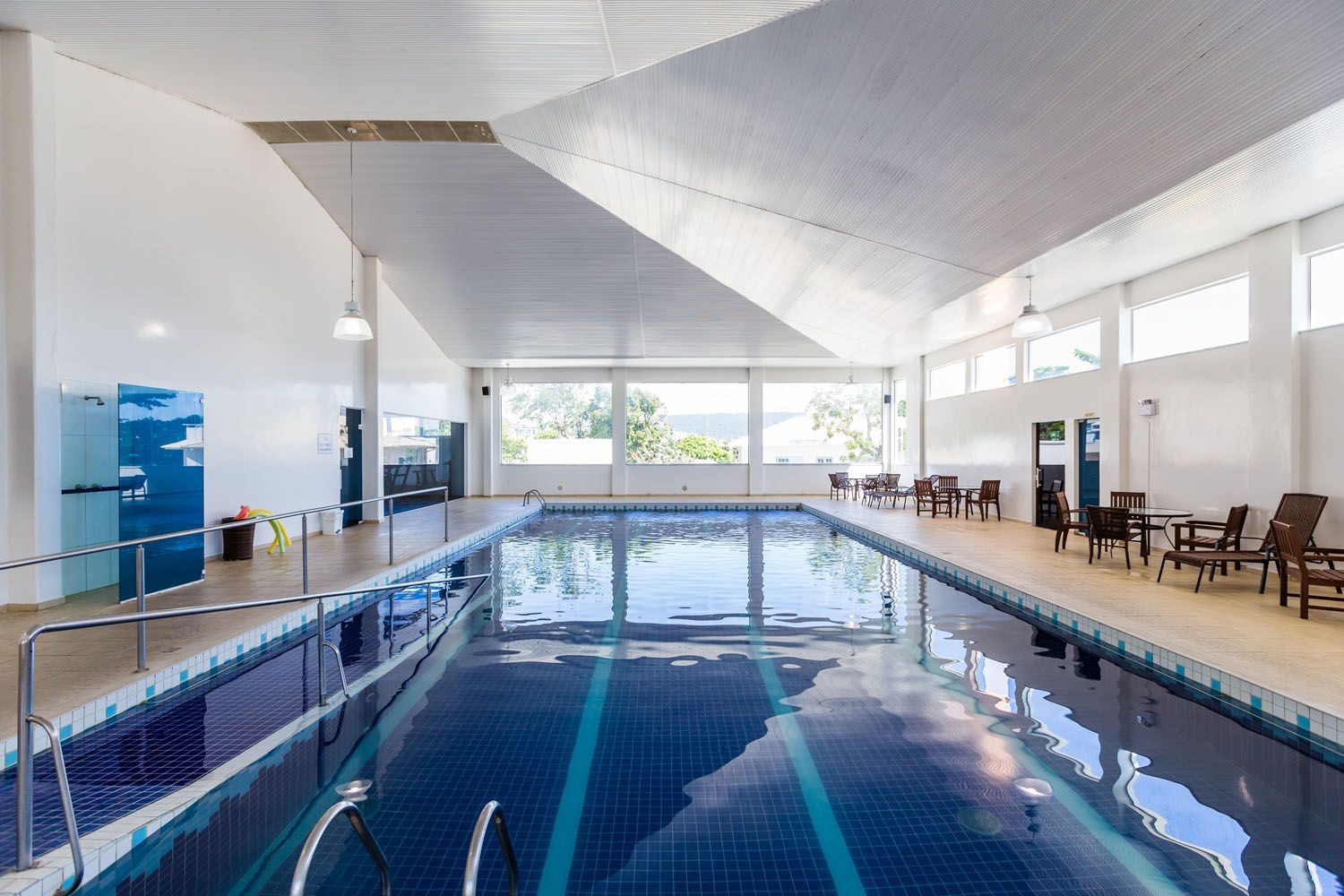 Uma grande piscina coberta com cadeiras e mesas ao redor.