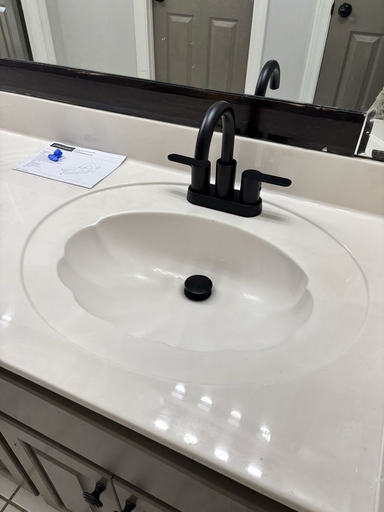 Bathroom sink with white countertop, black faucet, and mirror above it.