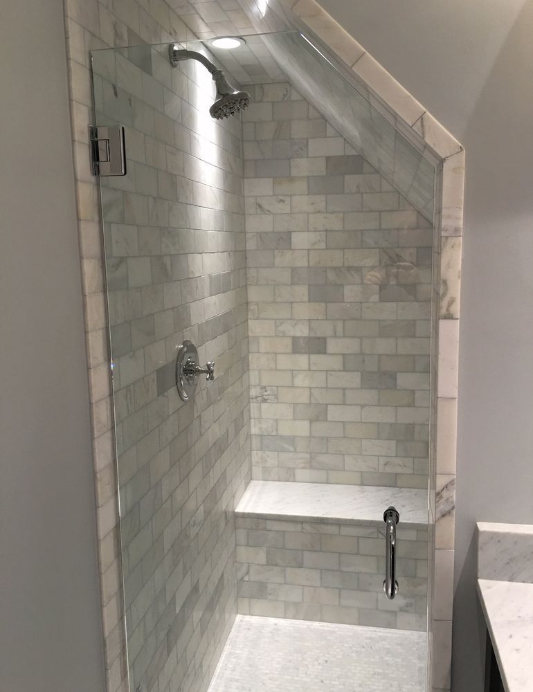 White-tiled walk-in shower with built-in bench, rainfall showerhead, and handheld sprayer