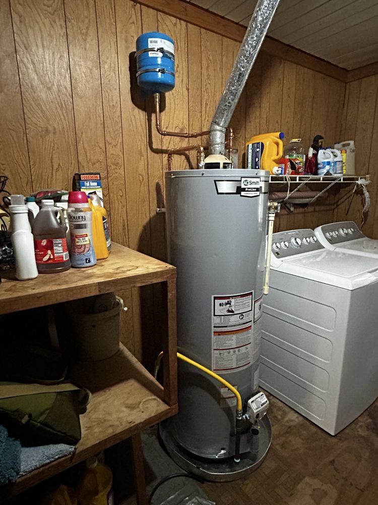 Utility room with gray water heater, white washer, and cleaning supplies on shelves