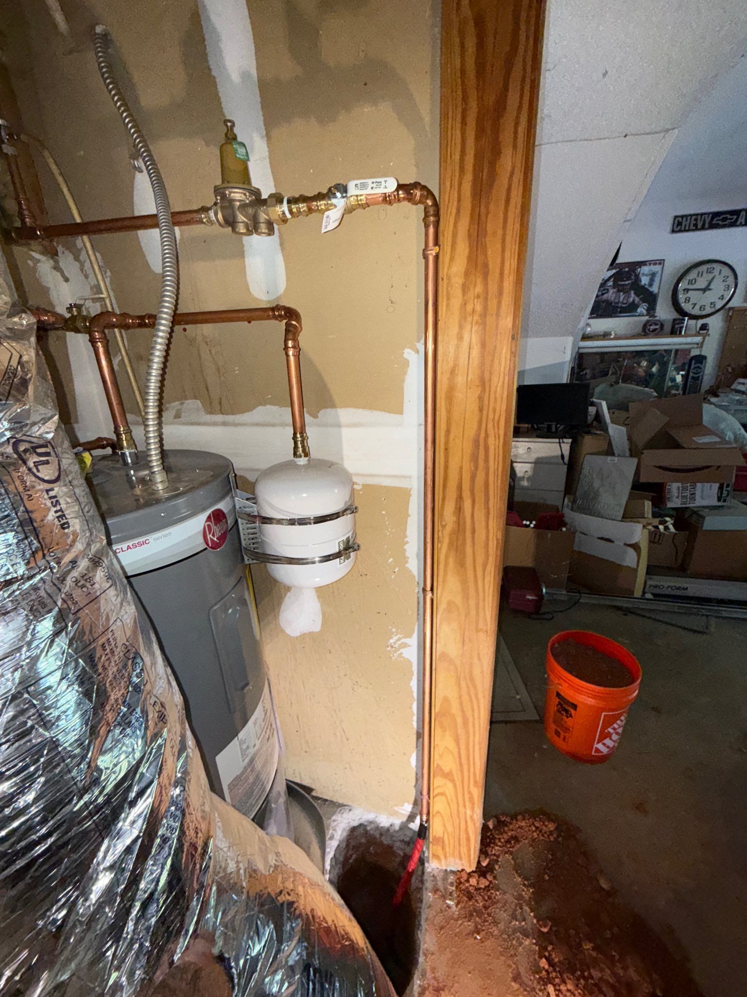 Basement utility area with copper pipes, water heater, and cluttered storage items.