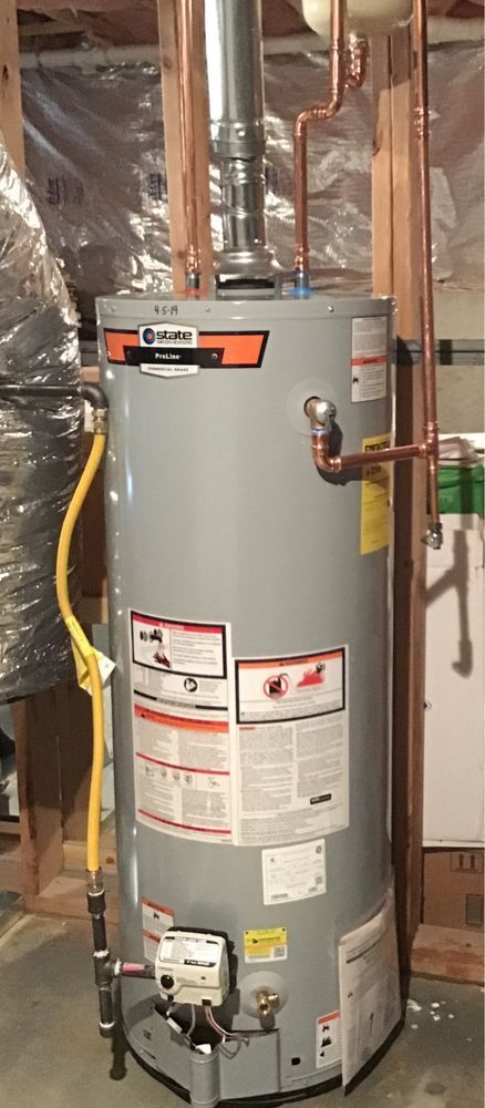 Gray water heater in a utility closet with exposed pipes and a yellow gas line.