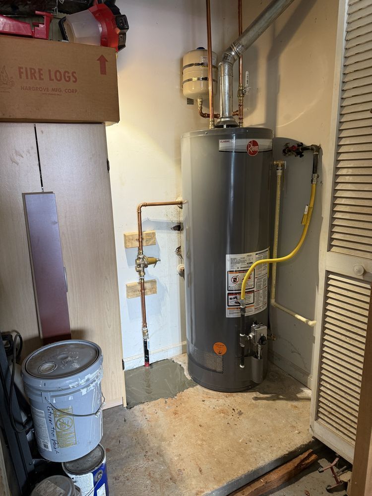 Water heater and utility piping in a small basement storage area.