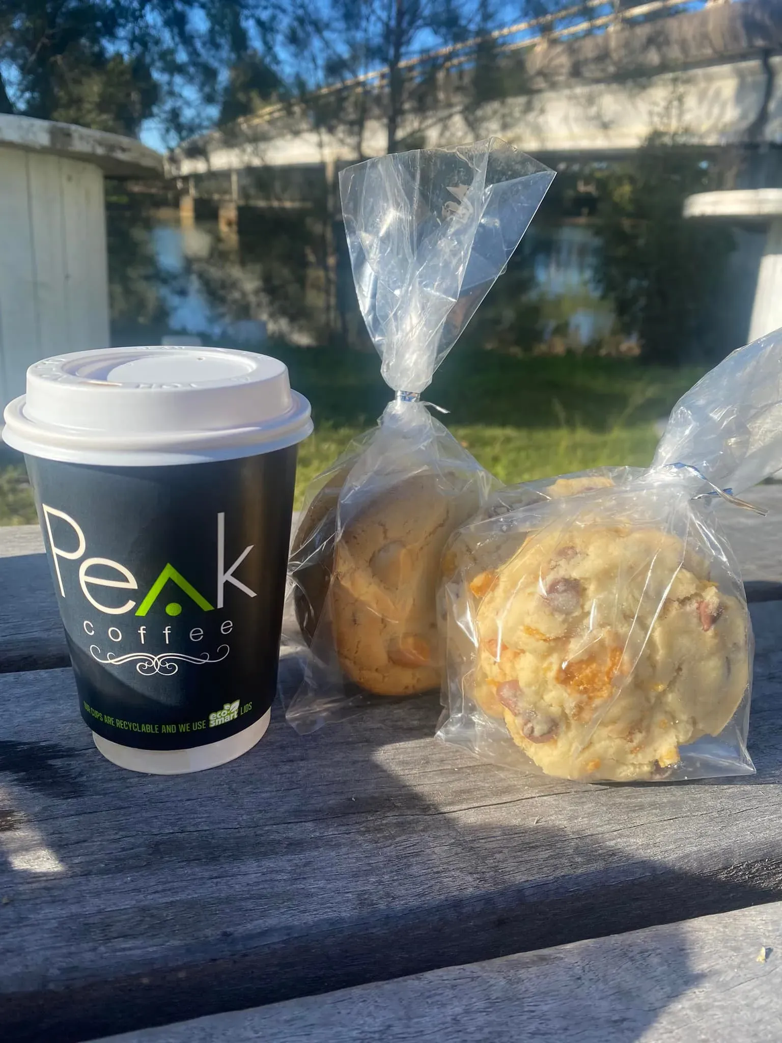 A Cup of Coffee and Two Cookies Are Sitting on a Wooden Table — Stones Oysters & Shed Takeaway in Harrington, NSW