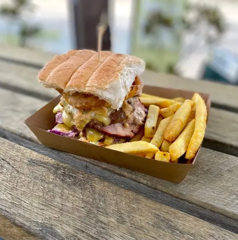 A Sandwich and French Fries Are Sitting on a Wooden Table — Stones Oysters & Shed Takeaway in Harrington, NSW