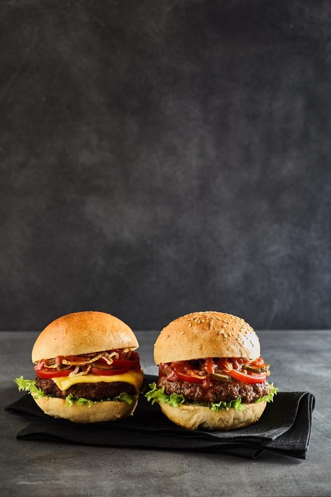 Two Hamburgers Are Sitting on A Black Napkin — Stones Oysters & Shed Takeaway in Harrington, NSW
