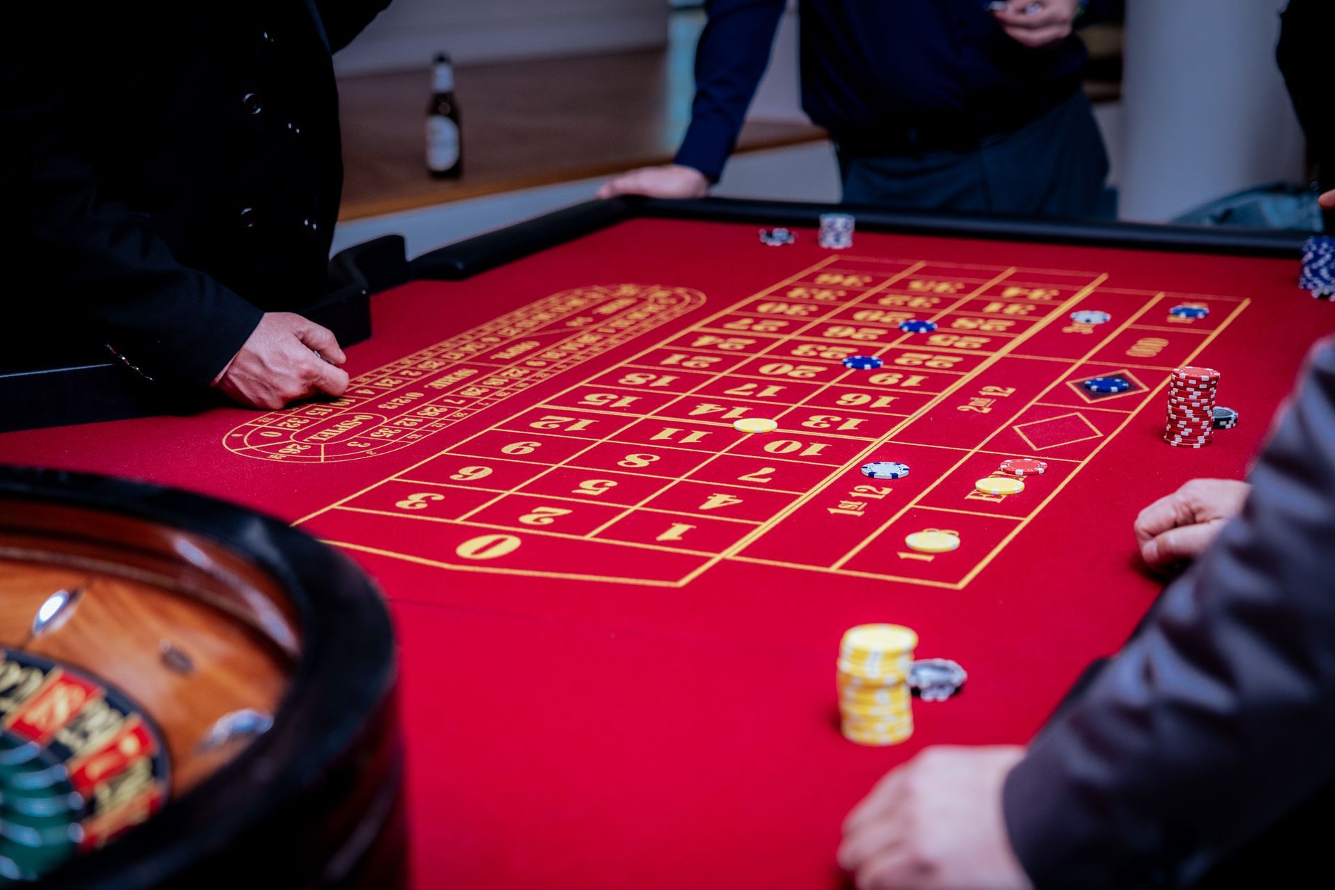 In einem Raum platzieren die Menschen Wetten mit bunten Spielchips auf einem Roulettetisch aus rotem Filz.
