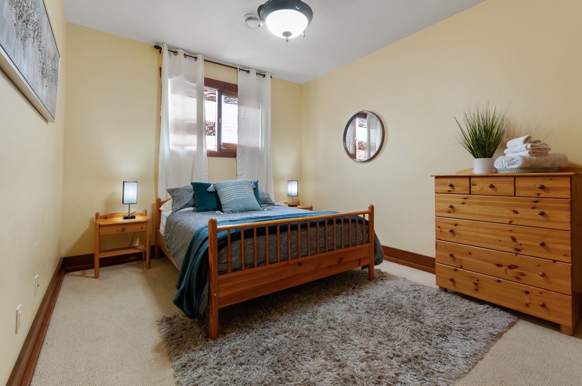Queen size bed in a guest room with a large wooden dresser