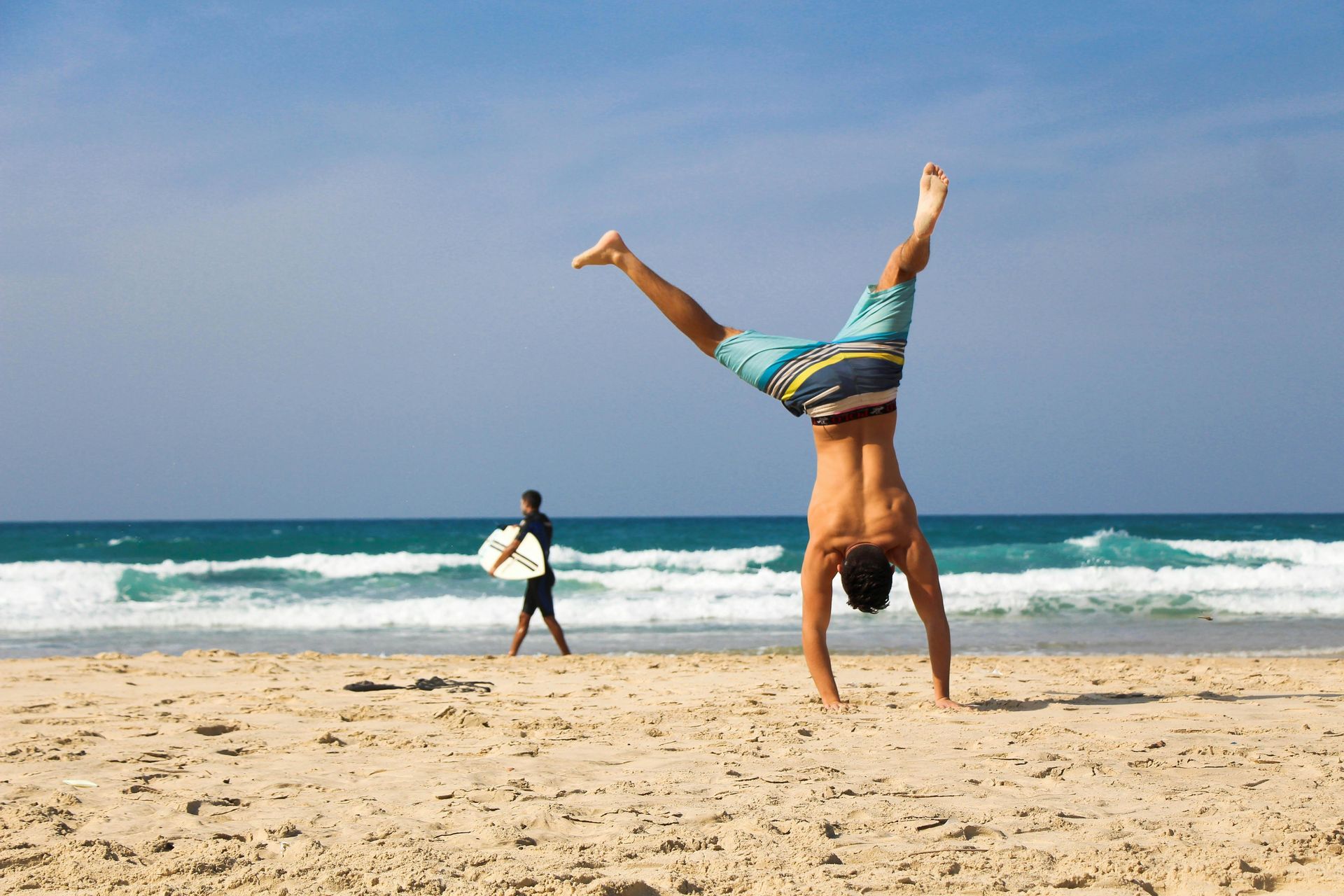 A man is doing a handstand on the beach.