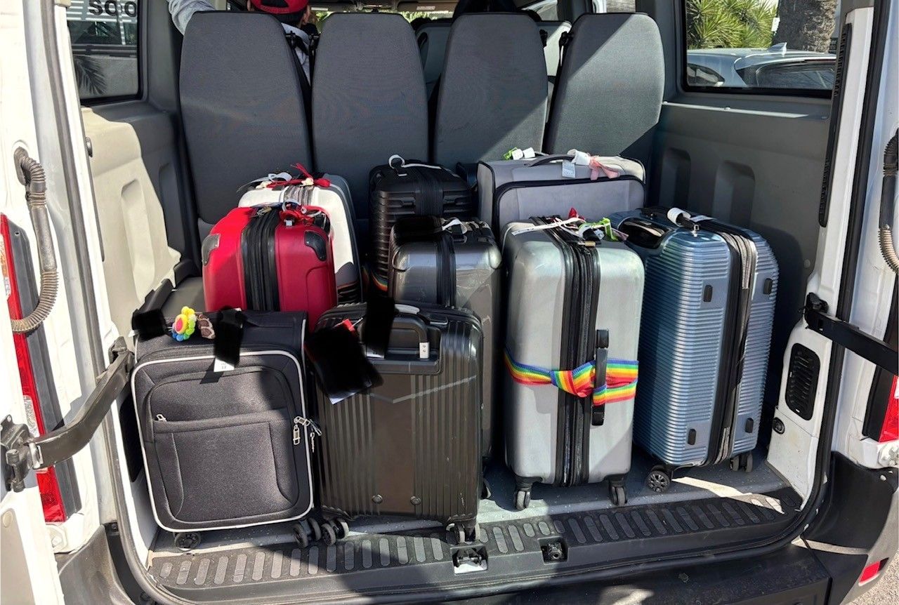 Photo of suitcases in the luggage compartment of a Ticket 2 Ride minibus.