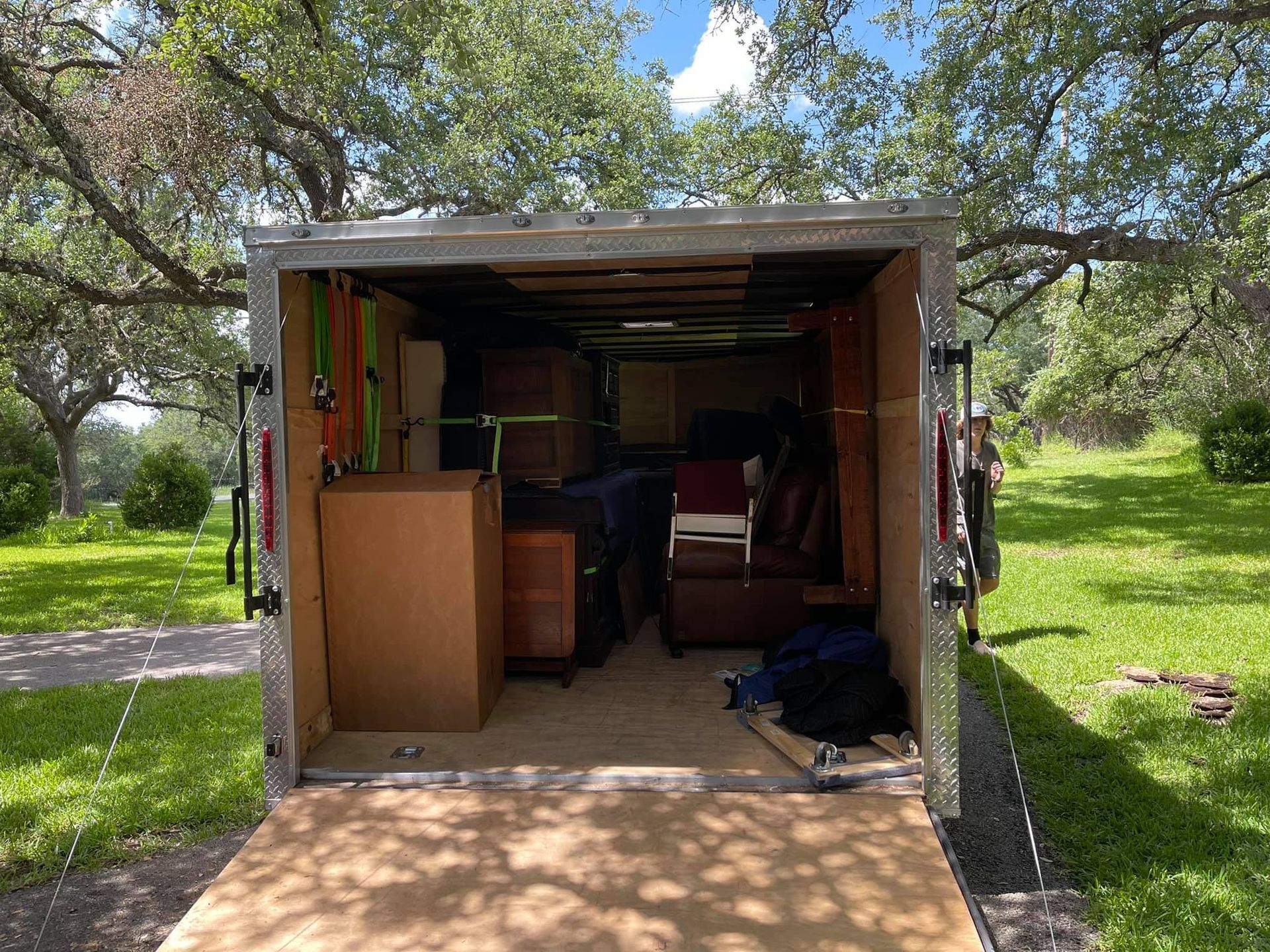 A trailer filled with furniture is parked in a grassy field.