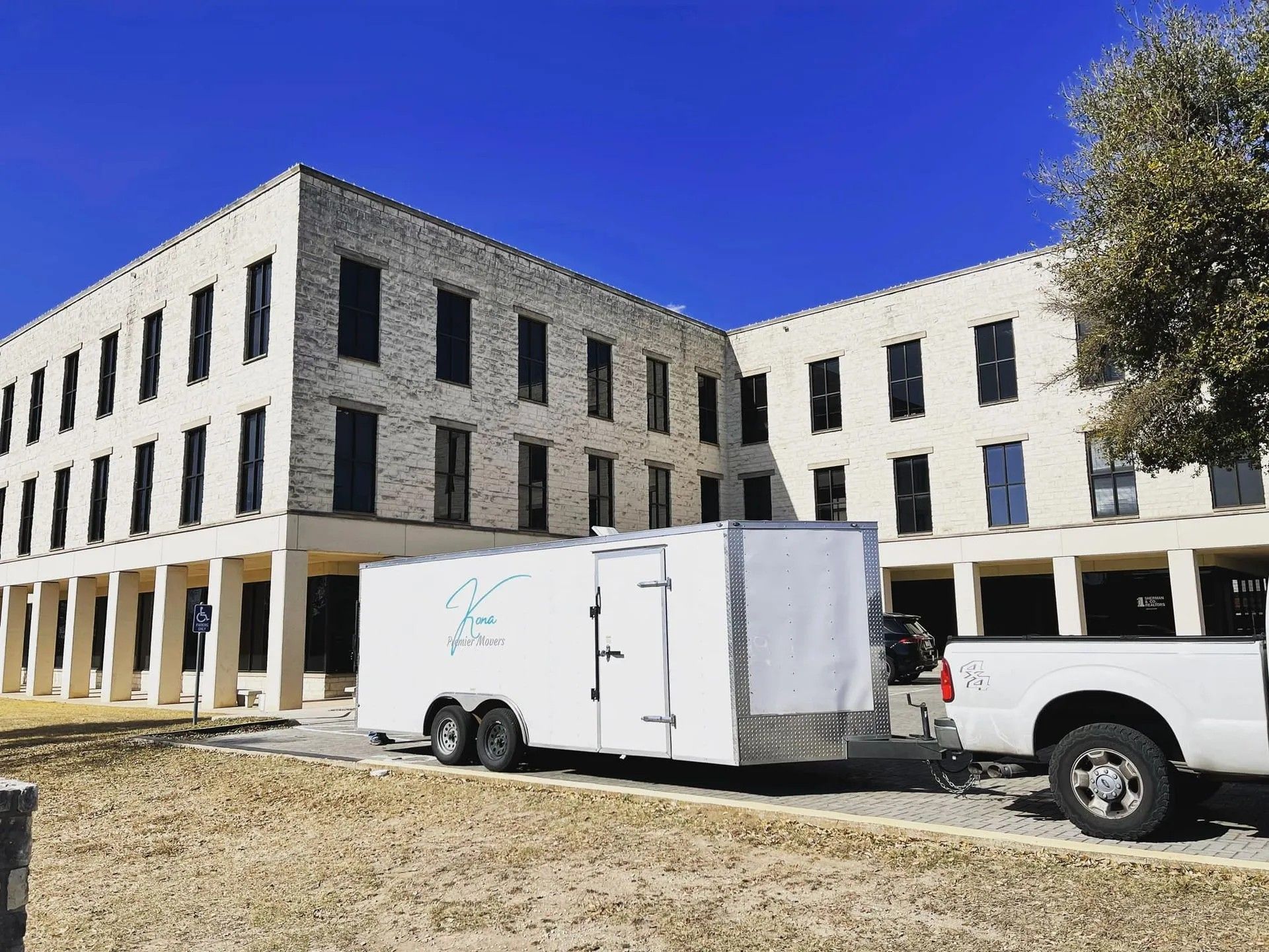 White construction building with parked trailer and pickup truck under a clear blue sky