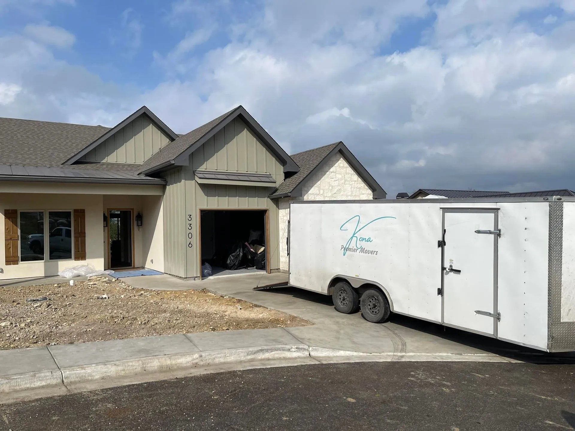 House under construction with a white trailer parked in the driveway and gravel landscaping.