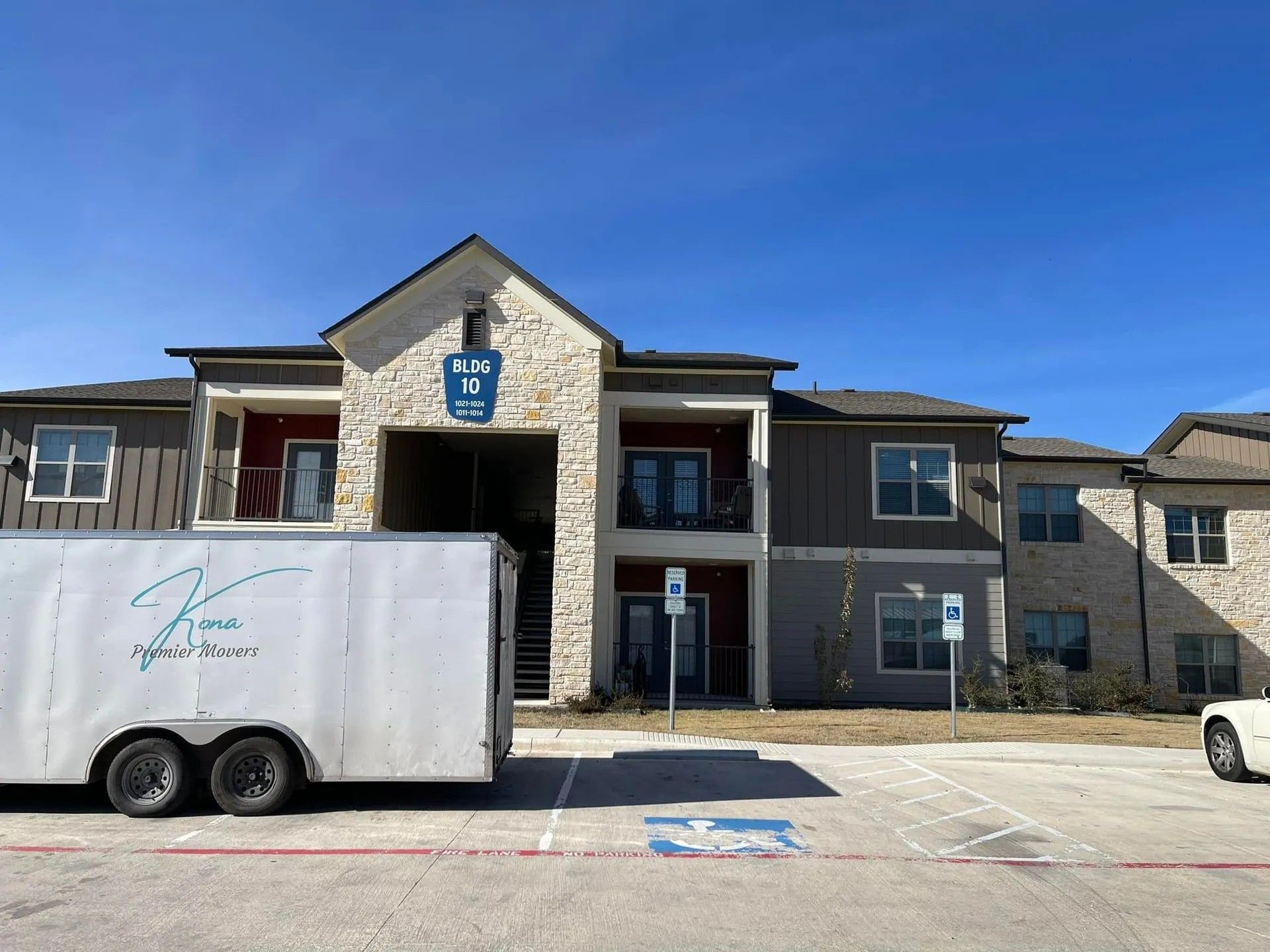 Apartment building with a white trailer parked in front under a clear blue sky