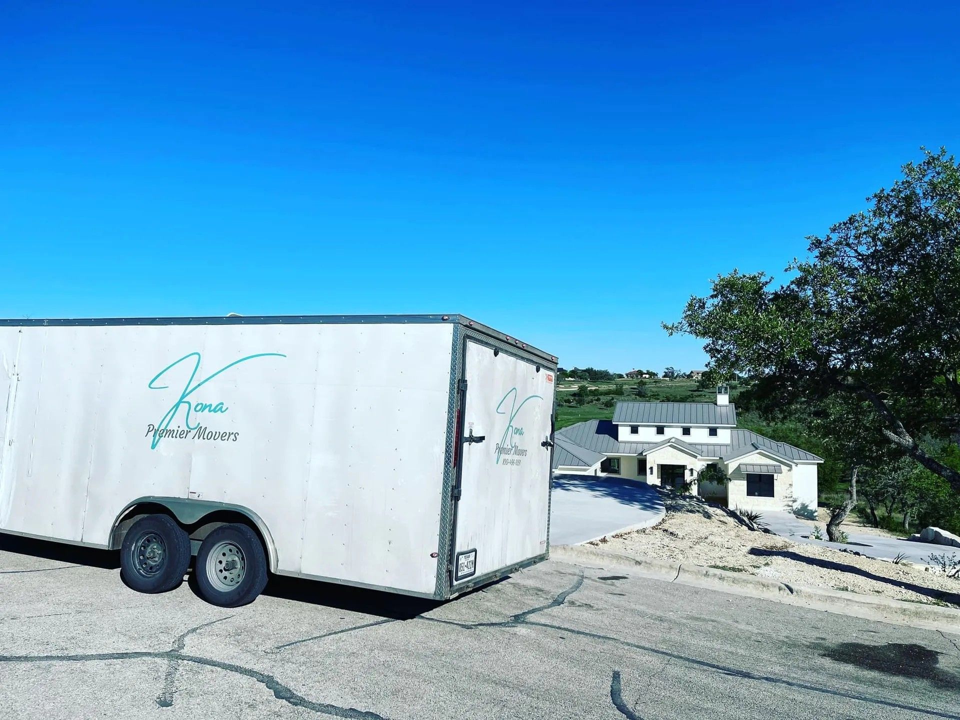 White trailer parked on cracked pavement overlooking a waterfront under a bright blue sky.