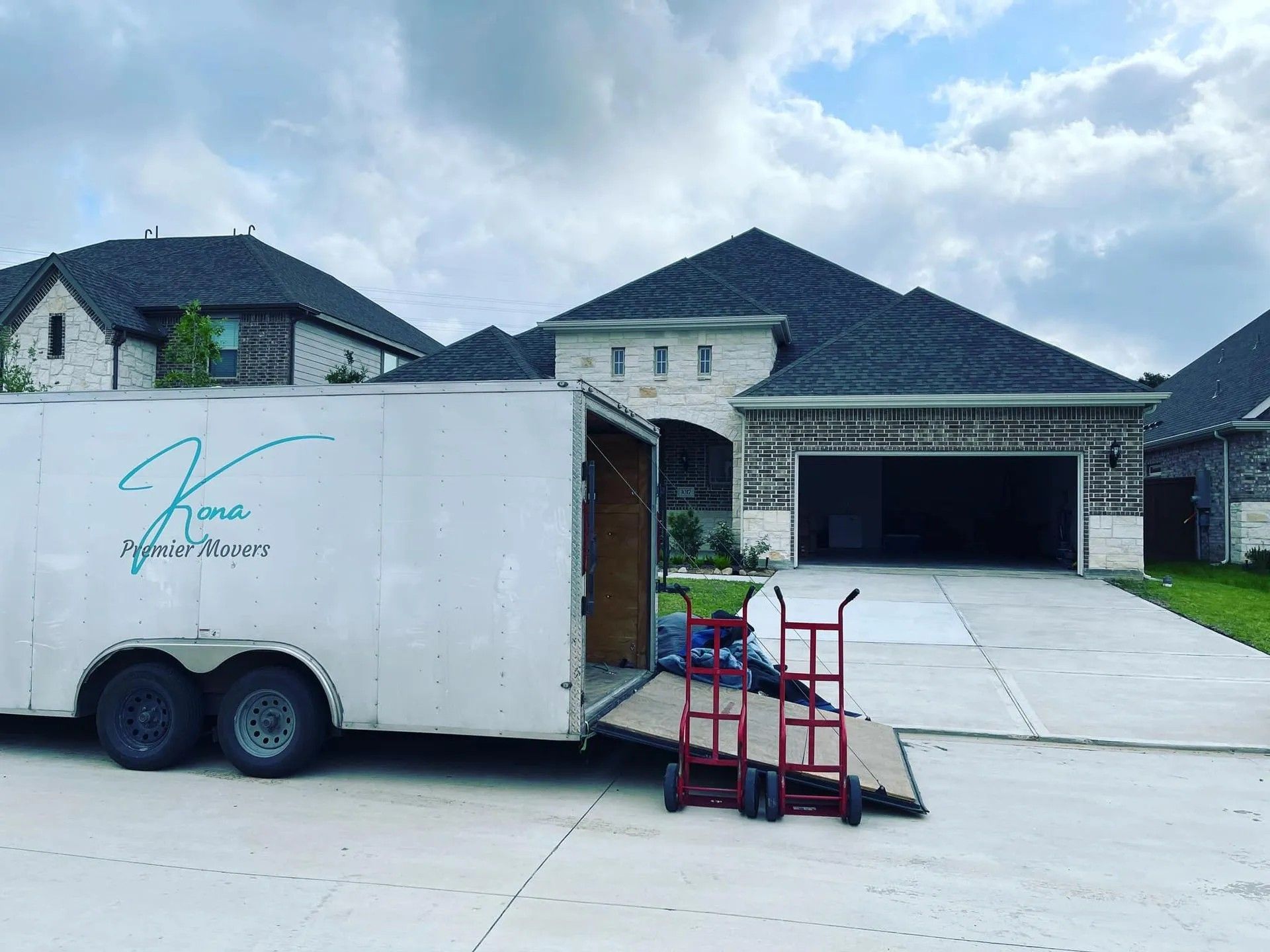 White trailer with ramp parked in front of a suburban house with an open garage