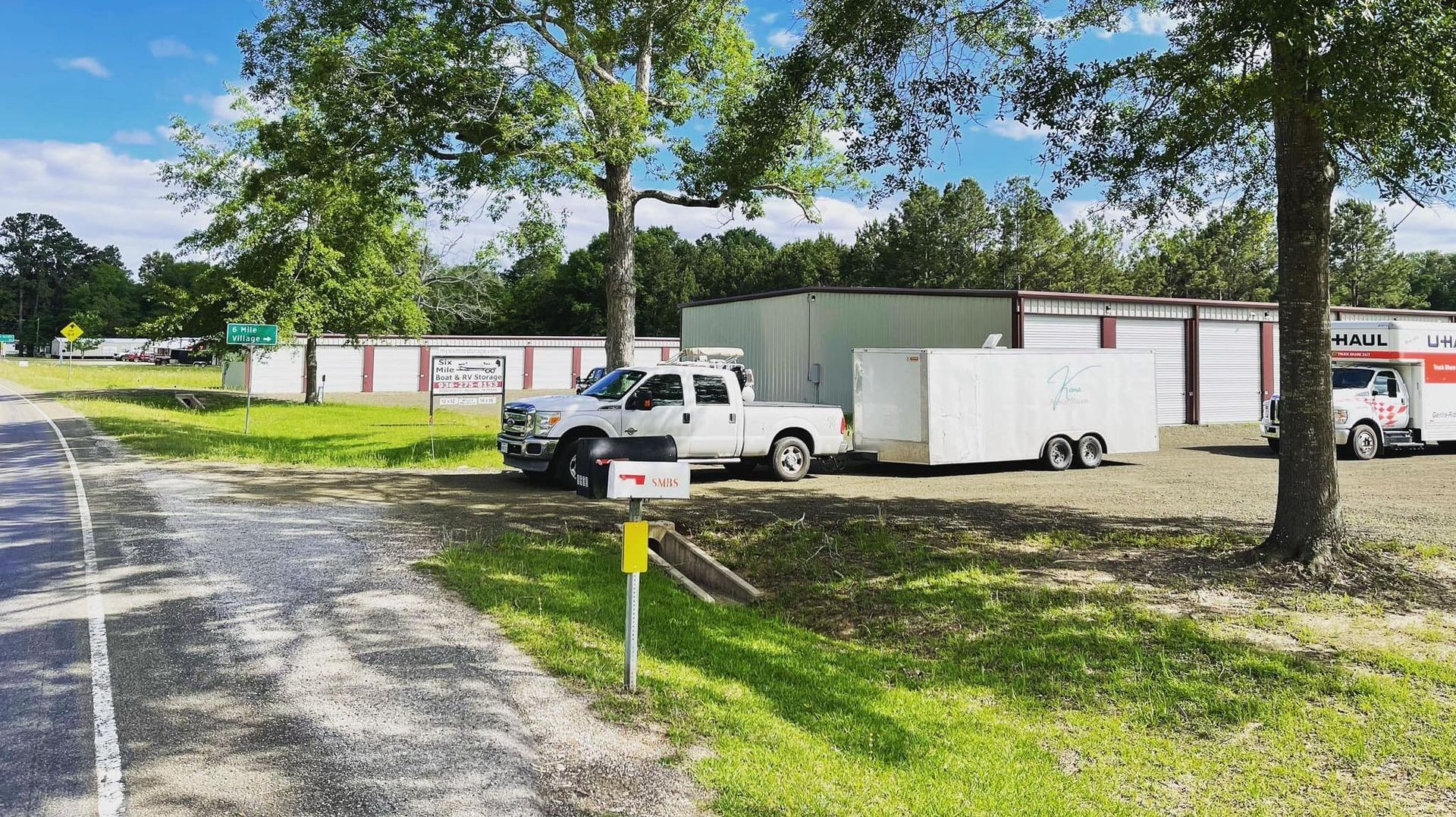 A truck is parked on the side of the road next to a trailer.