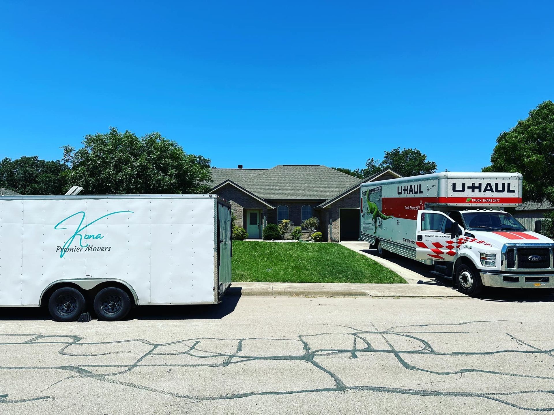 U-Haul truck and trailer parked in front of a suburban house on a sunny day