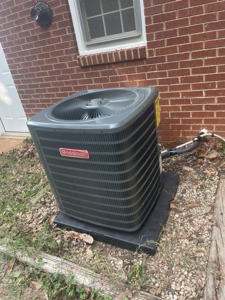 An air conditioner is sitting on the side of a brick building.