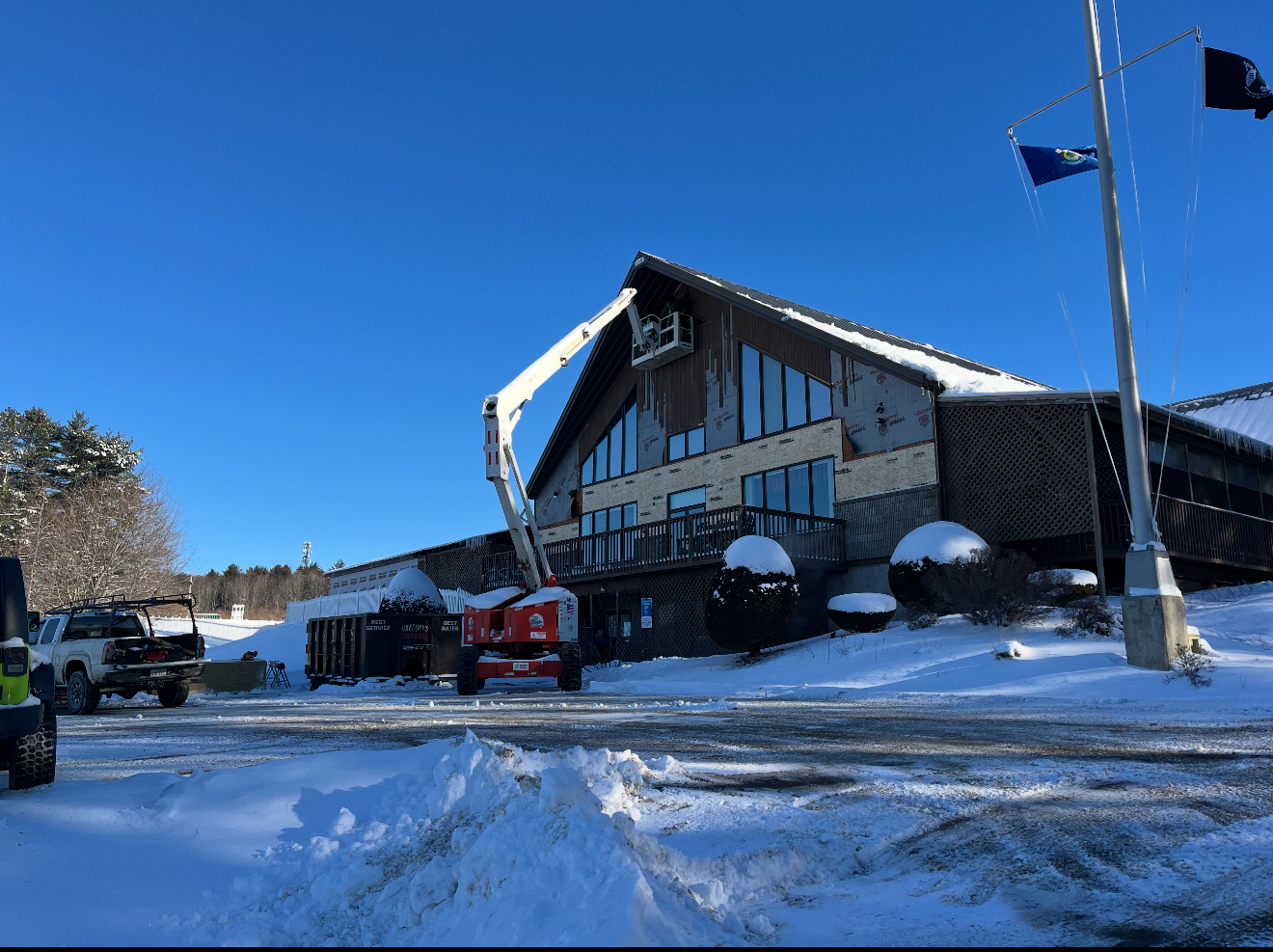 Snowy exterior of a building with construction equipment; clear blue sky.