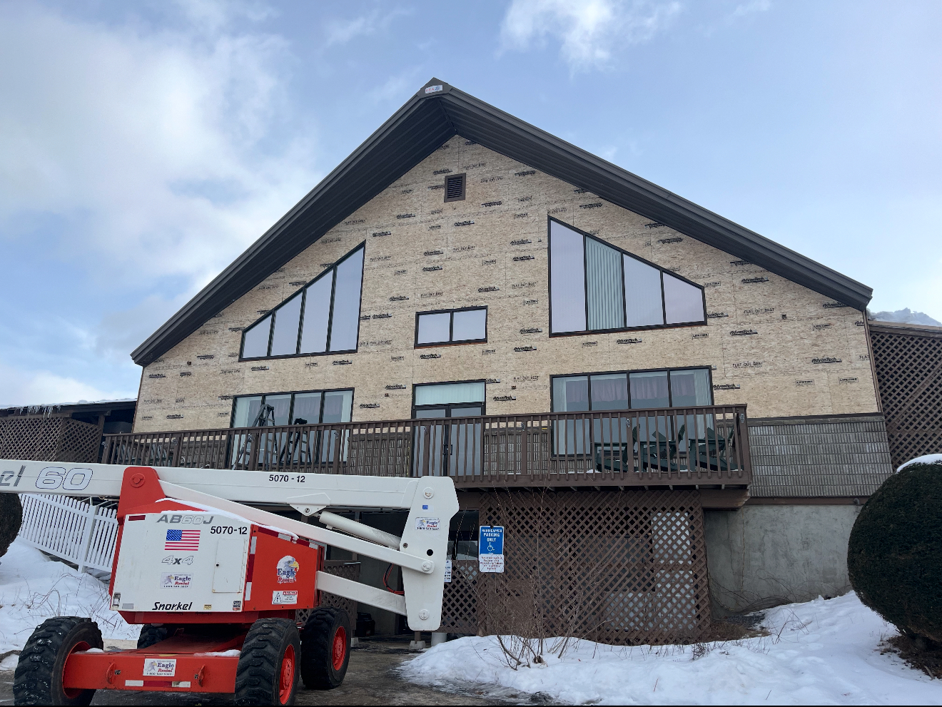 Building with dark brown roof, tan brick exterior, and large windows. A lift is in front, with snow on the ground.