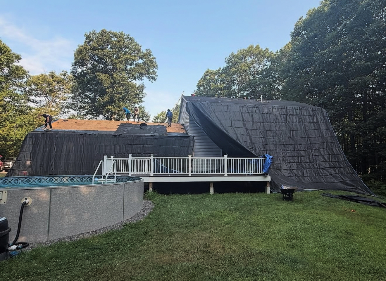House with pool under construction, covered in black tarp; sunny day.