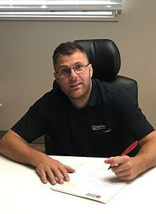 Un homme est assis à un bureau avec un stylo à la main.