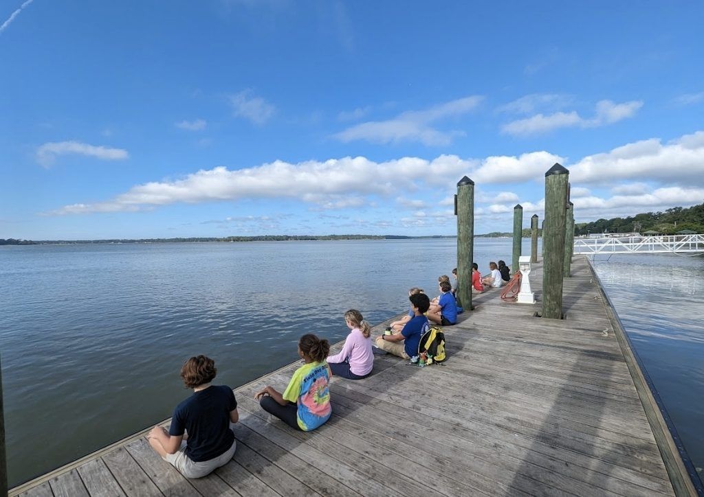 A group of people are sitting on a dock overlooking a body of water.