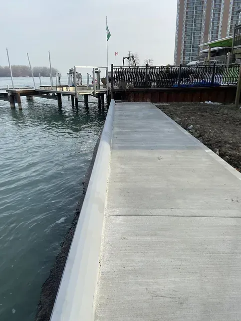 A concrete walkway leading to a dock next to a body of water.