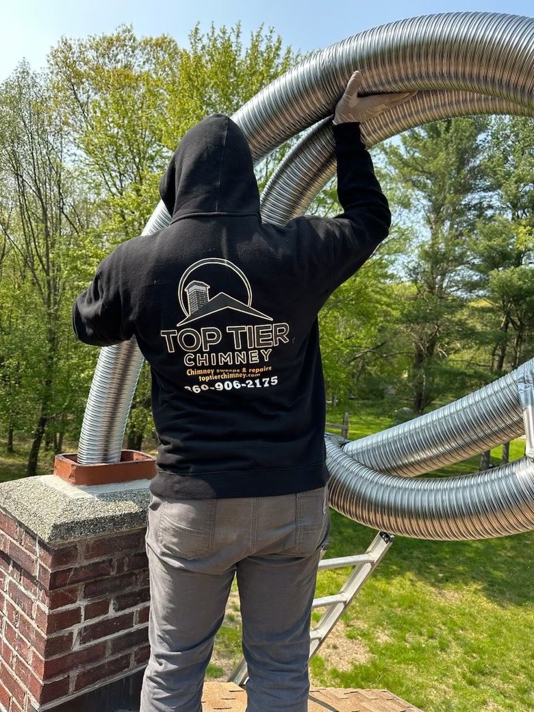 Worker on a ladder repairing a rooftop chimney on a house