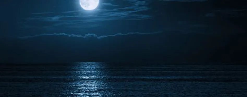 A full moon is shining over the ocean at night Full moon over ocean at night during Reel Groovy night fishing in Panama City Beach