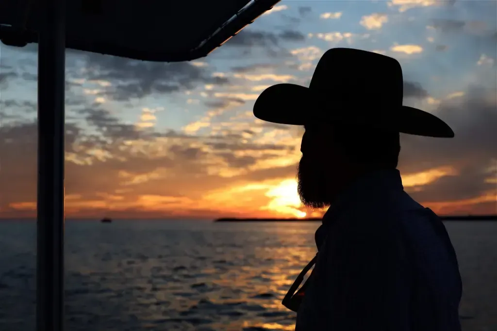 Man in cowboy hat watching sunset on best sunset cruise Panama City Beach with Reel Groovy Experiences