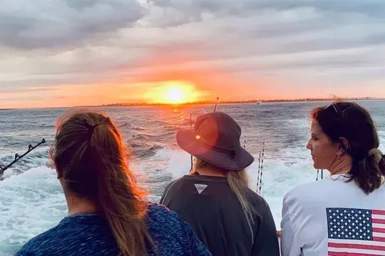 Three women on a Panama City Beach fishing charter with Reel Groovy, sunset over the ocean