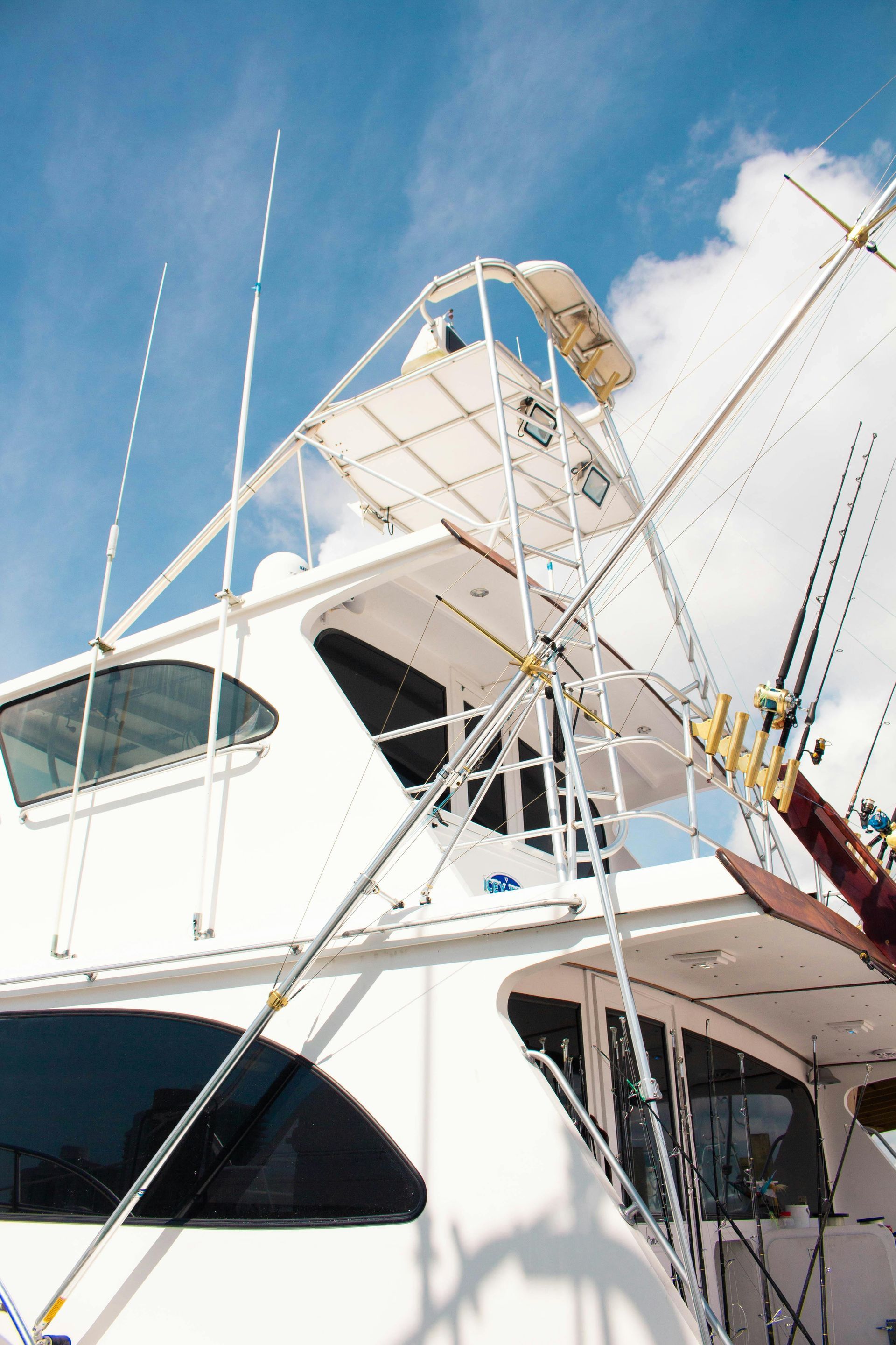 White yacht with fishing rods and a ladder against a blue sky