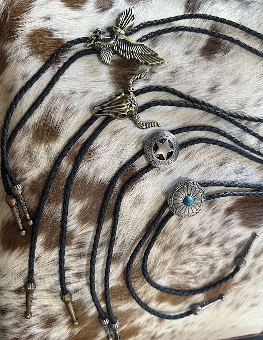 A Group of Bolo Tie Necklaces Are Sitting on Top of A Cowhide Blanket — Country Charm in Charmhaven, NSW