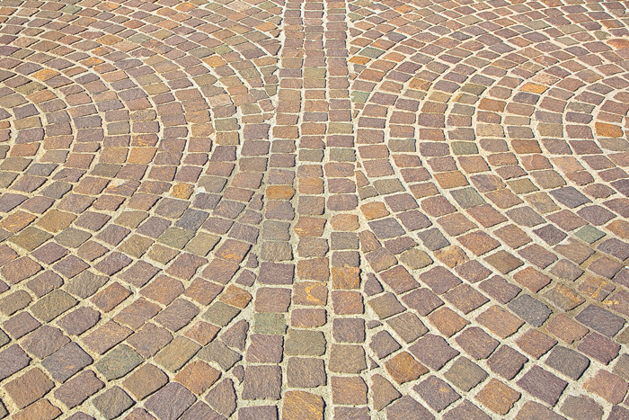 Curved brick pavement in tan, brown, and gray tones forming a symmetrical pattern