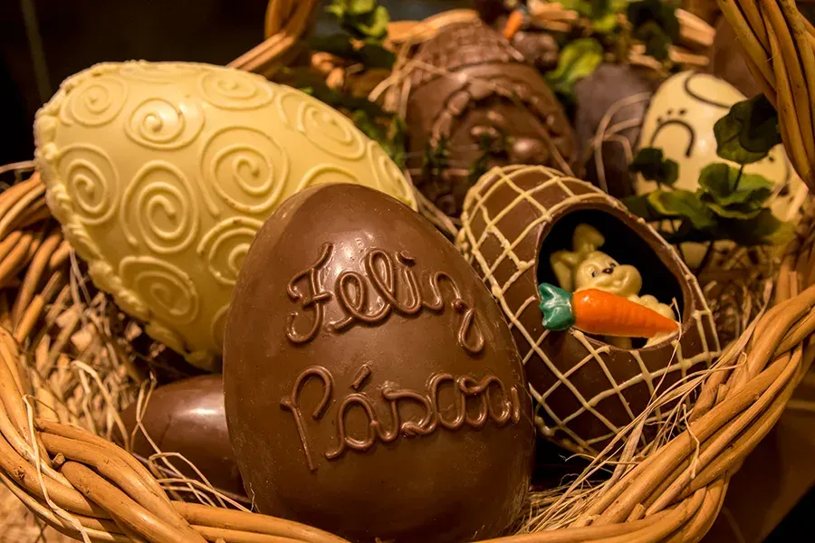 Uma cesta de vime cheia de ovos de Páscoa de chocolate decorados, incluindo um com a inscrição 