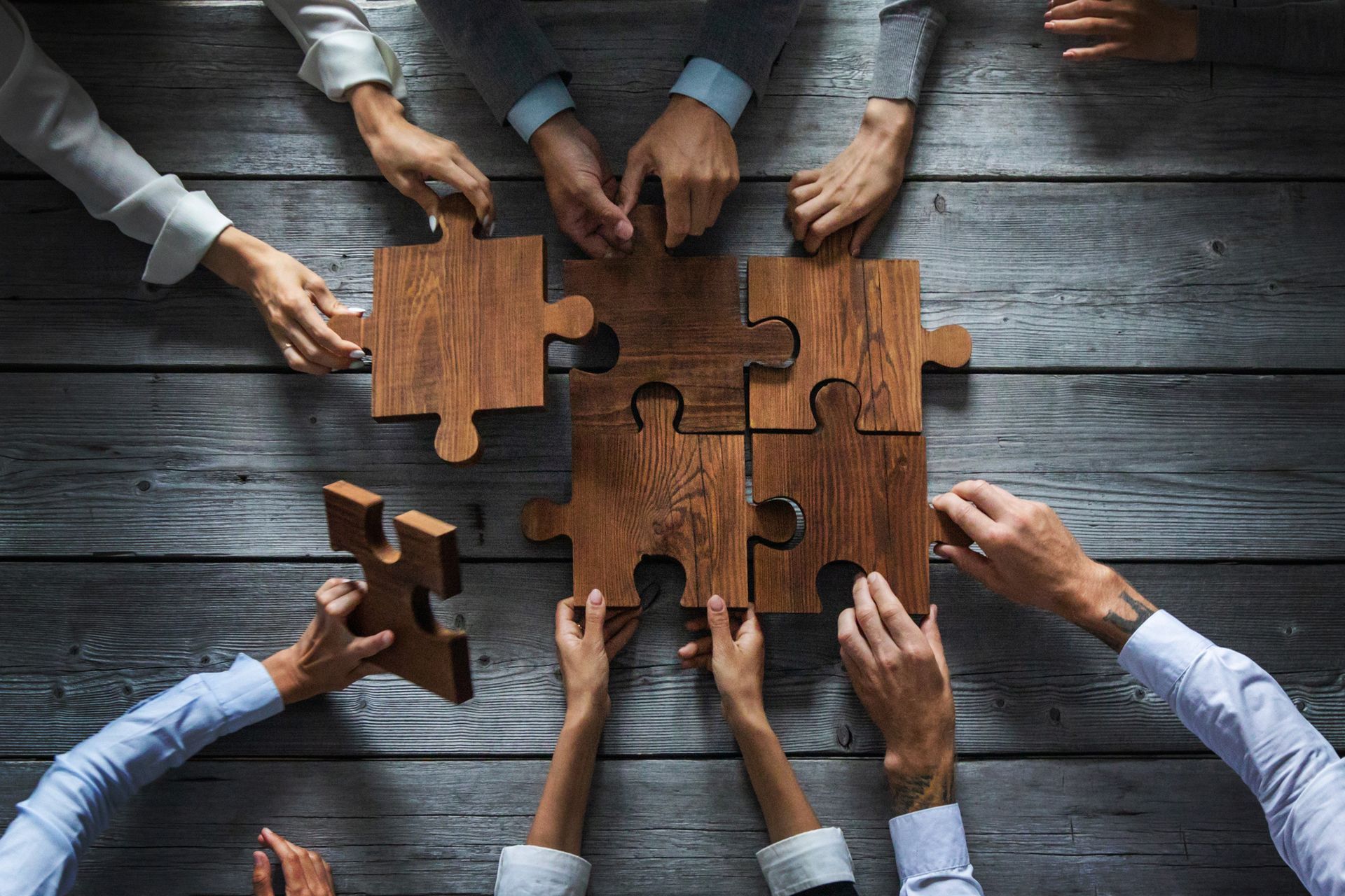 Mensen leggen grote puzzelstukken op hun plek. Communiceren is vaak een puzzel.