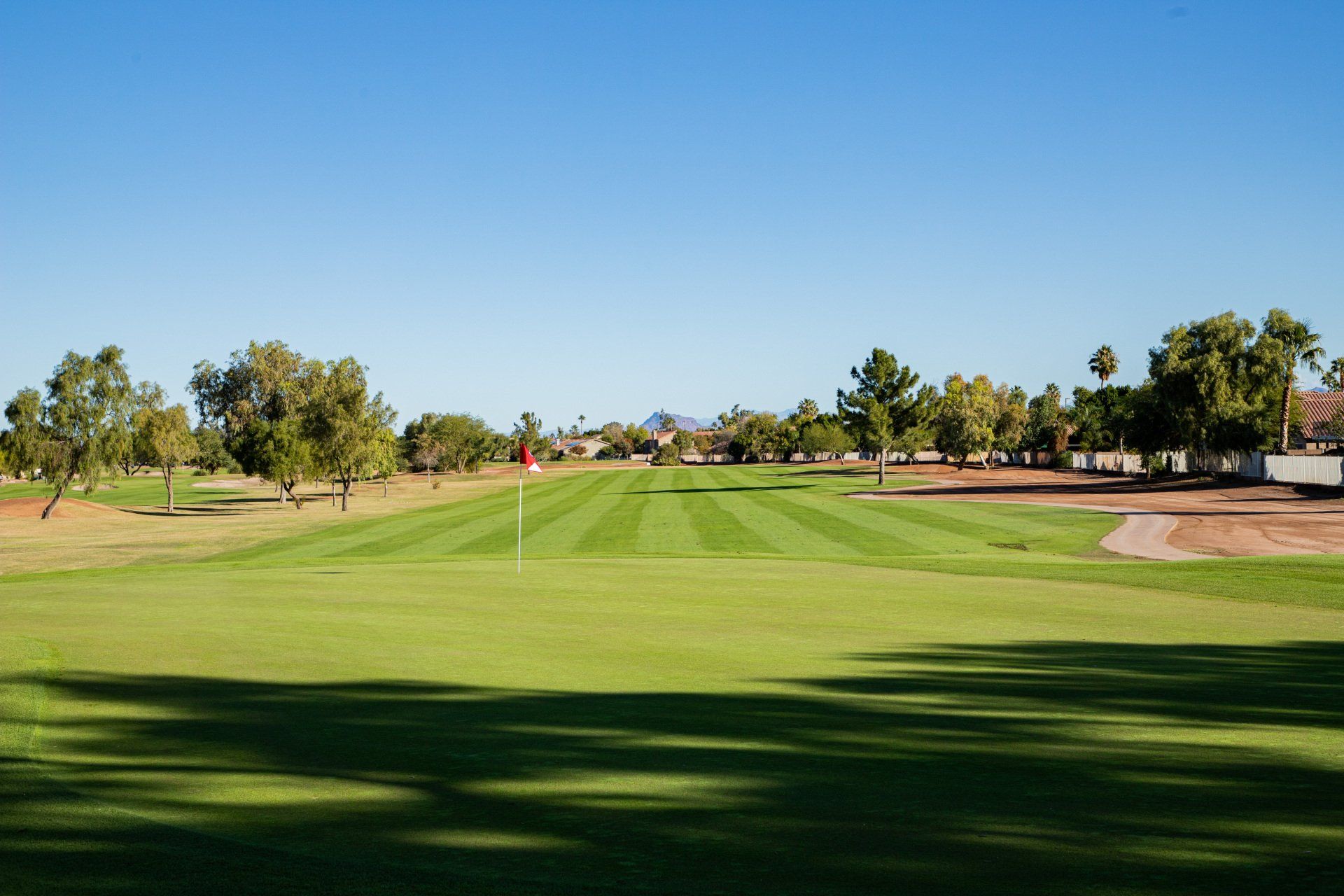 A golf course with a lot of green grass and trees in the background.