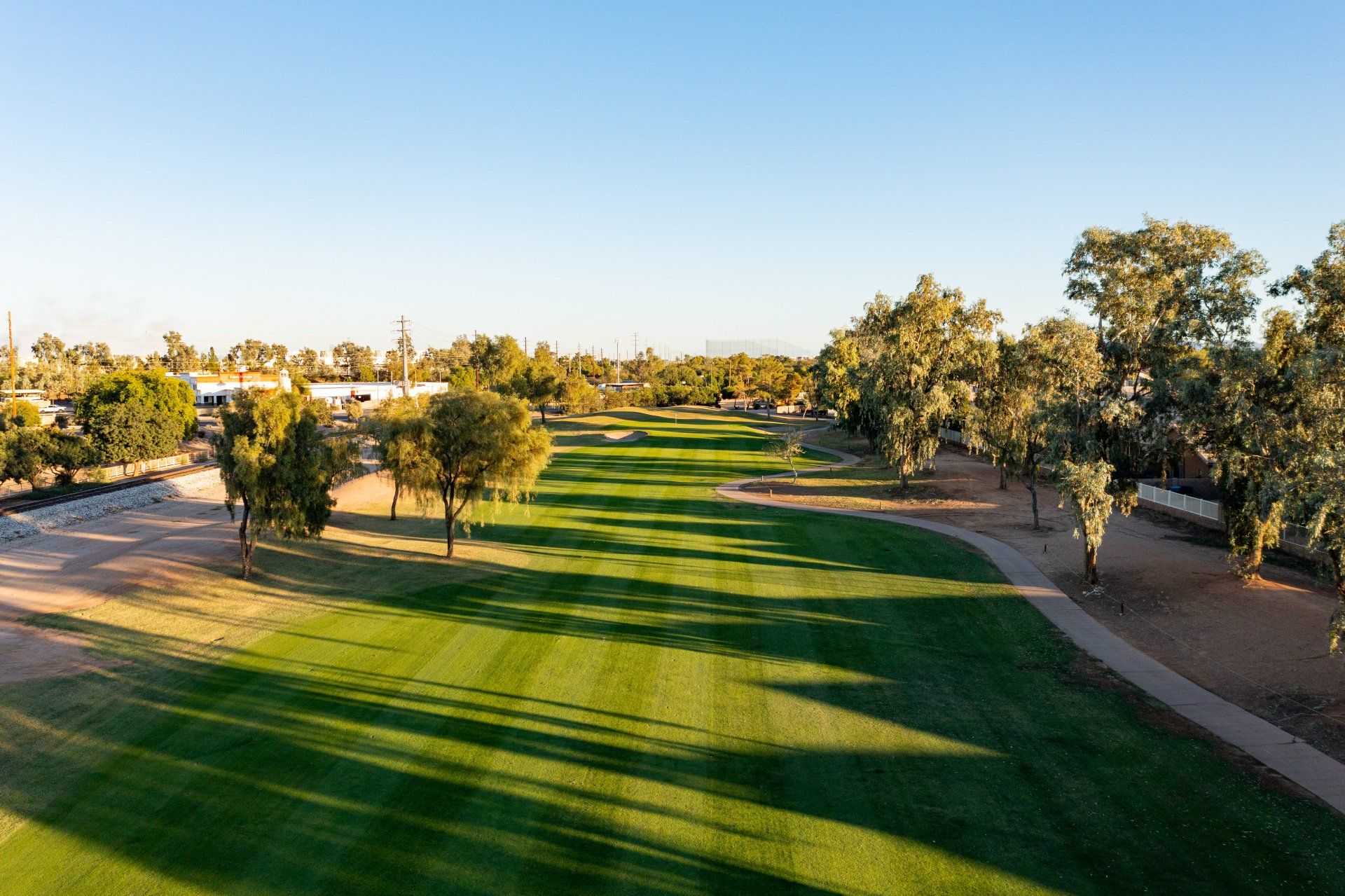 An aerial view of a golf course with trees and a path.